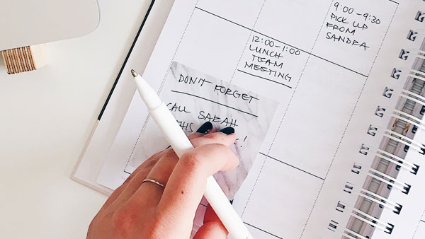 Woman putting a post it into a appointment calendar