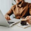 Man working on a laptop computer holding a cup of coffee